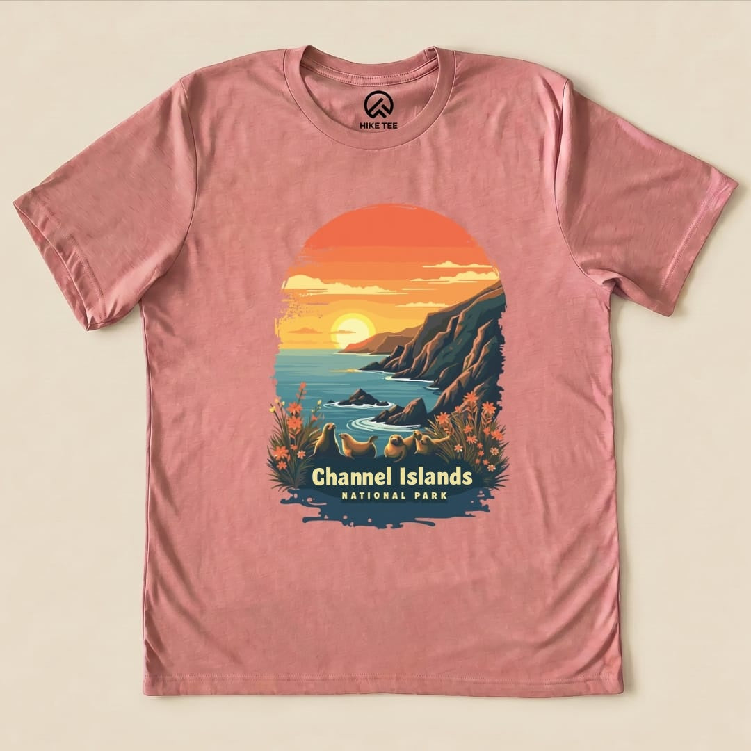A pink graphic t-shirt featuring a vibrant sunset over a coastal scene with sea lions and the text "Channel Islands National Park.