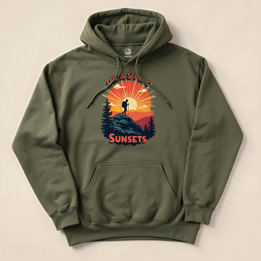 The Chasing Sunsets Hoodie is an olive green graphic sweatshirt featuring a silhouette of a hiker against a sunset backdrop.