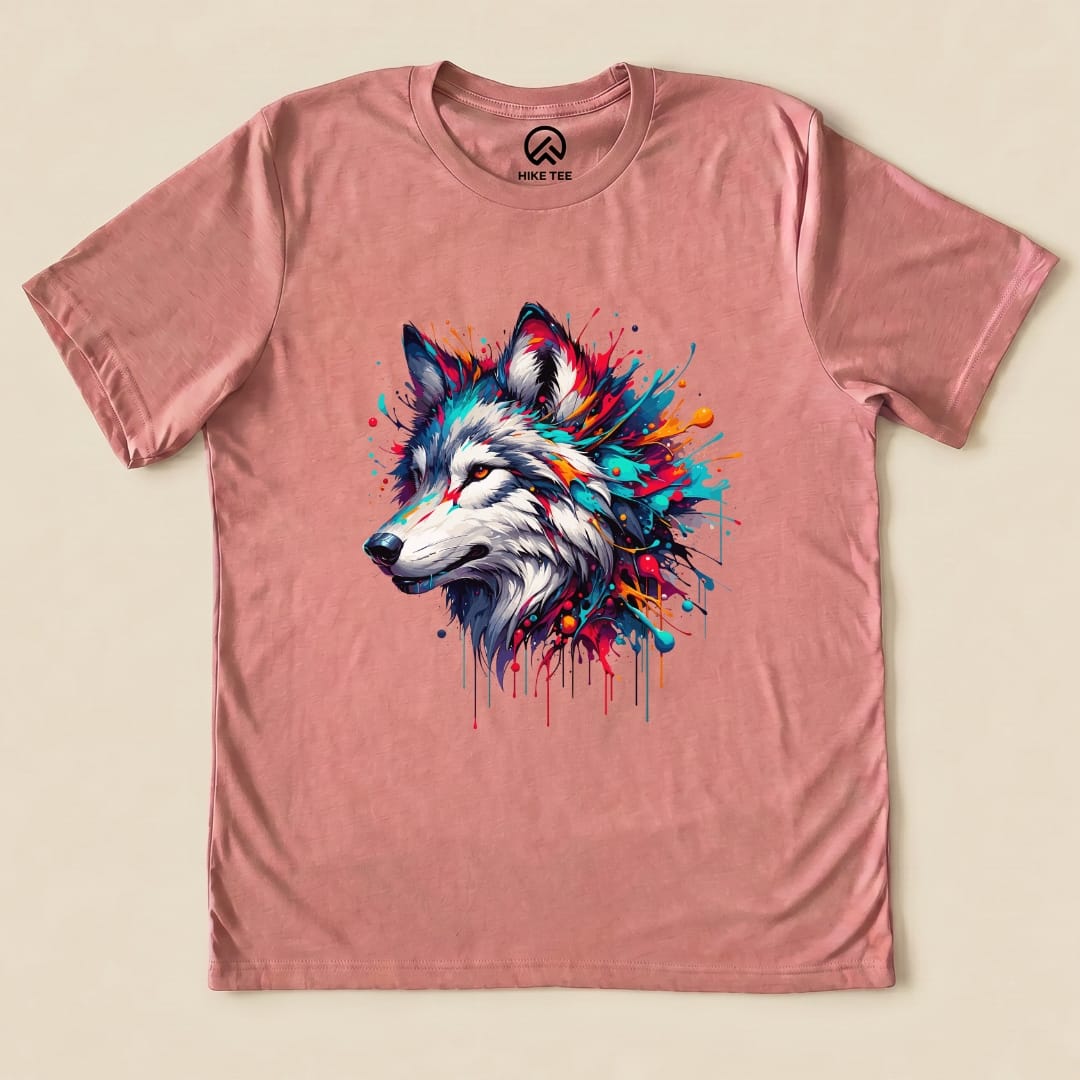 A colorful wolf graphic is prominently featured on a pink graphic t-shirt from Hike Tee, showcasing vibrant splashes of paint.