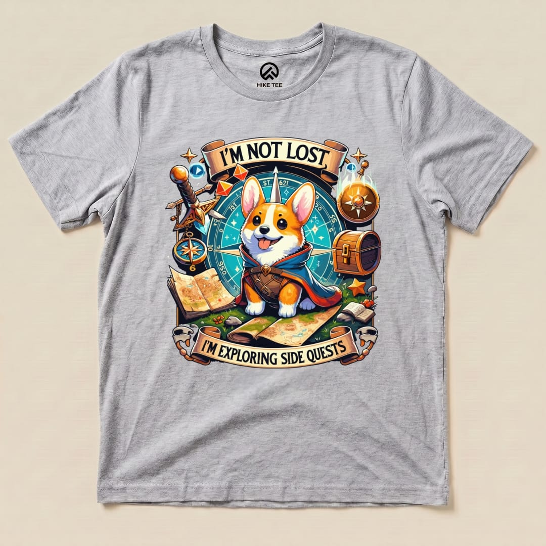 A graphic t-shirt featuring a playful corgi with the text "I'M NOT LOST, I'M EXPLORING SIDE QUESTS" surrounded by adventure-themed elements.