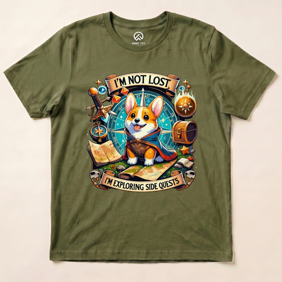 A graphic t-shirt featuring a cute corgi with a cape and the slogan "I'M NOT LOST, I'M EXPLORING SIDE QUESTS" on an olive background.
