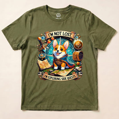 A graphic t-shirt featuring a cute corgi with a cape and the slogan "I'M NOT LOST, I'M EXPLORING SIDE QUESTS" on an olive background.