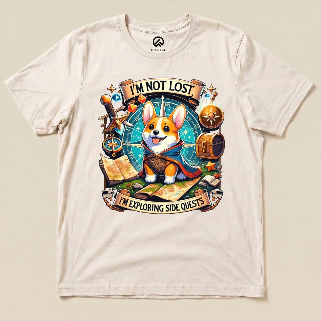 The graphic t-shirt features a playful corgi in a cape surrounded by a compass, maps, and the slogan "I'm Not Lost, I'm Exploring Side Quests.