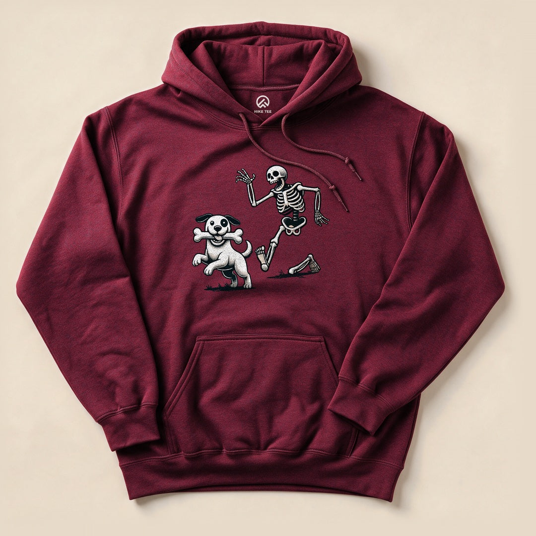 A maroon hoodie featuring a graphic of a skeleton playing with a dog and a bone, titled "Skeleton and Dog Halloween Hoodie.