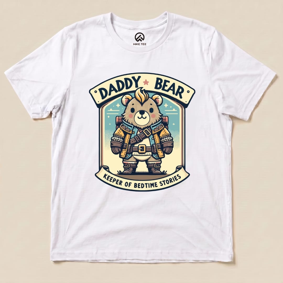 A white graphic t-shirt featuring a cartoon bear in explorer gear, labeled "Daddy Bear: Keeper of Bedtime Stories.