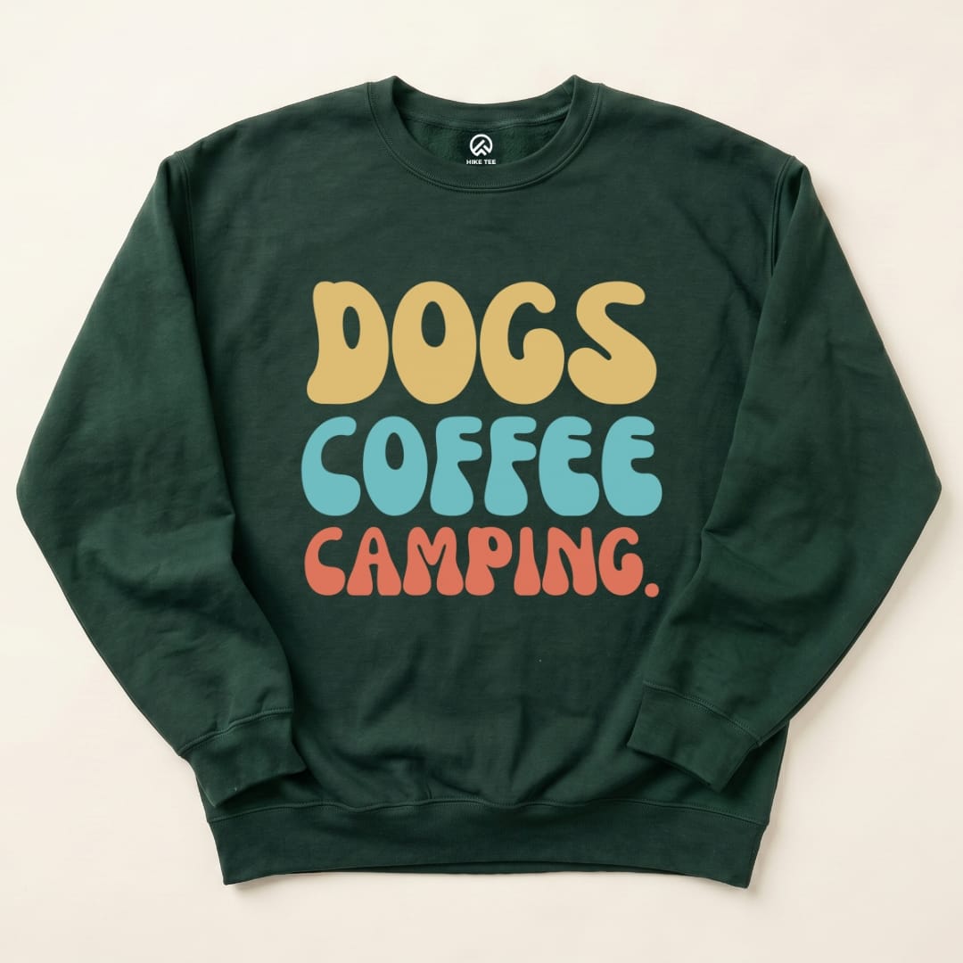 A dark green graphic t-shirt features the playful text "DOGS COFFEE CAMPING" in vibrant colors, perfect for outdoor enthusiasts.