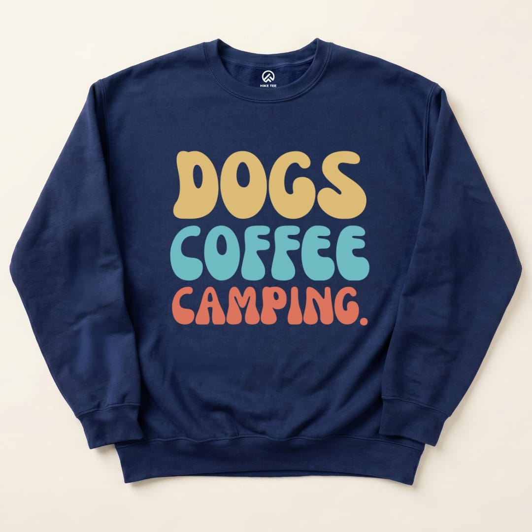 Graphic t-shirt featuring the bold text "DOGS COFFEE CAMPING" in playful colors on a navy background.