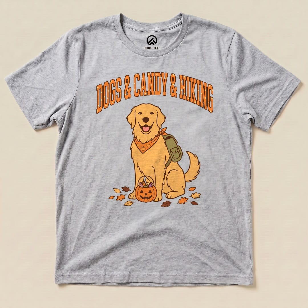 A graphic t-shirt featuring a cheerful golden retriever with a pumpkin basket and the words "Dogs & Candy & Hiking" above.