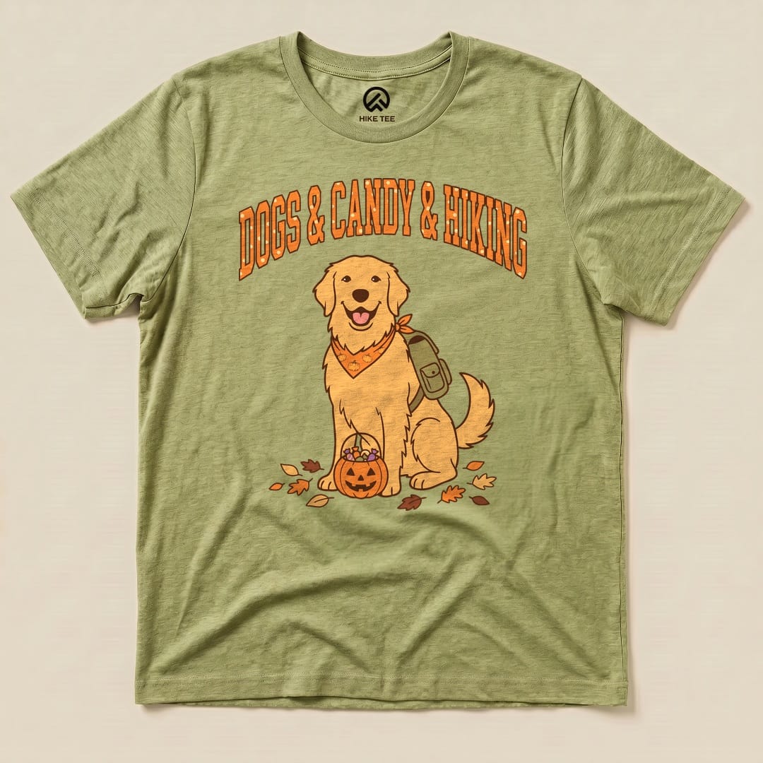 A graphic t-shirt featuring a golden retriever wearing a bandana, with the text "Dogs & Candy & Hiking" above and autumn leaves.