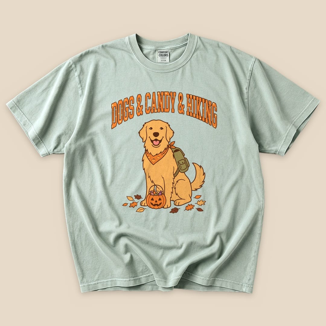 A mint green graphic t-shirt featuring a smiling golden retriever with a backpack and a pumpkin, stating "Dogs & Candy & Hiking.
