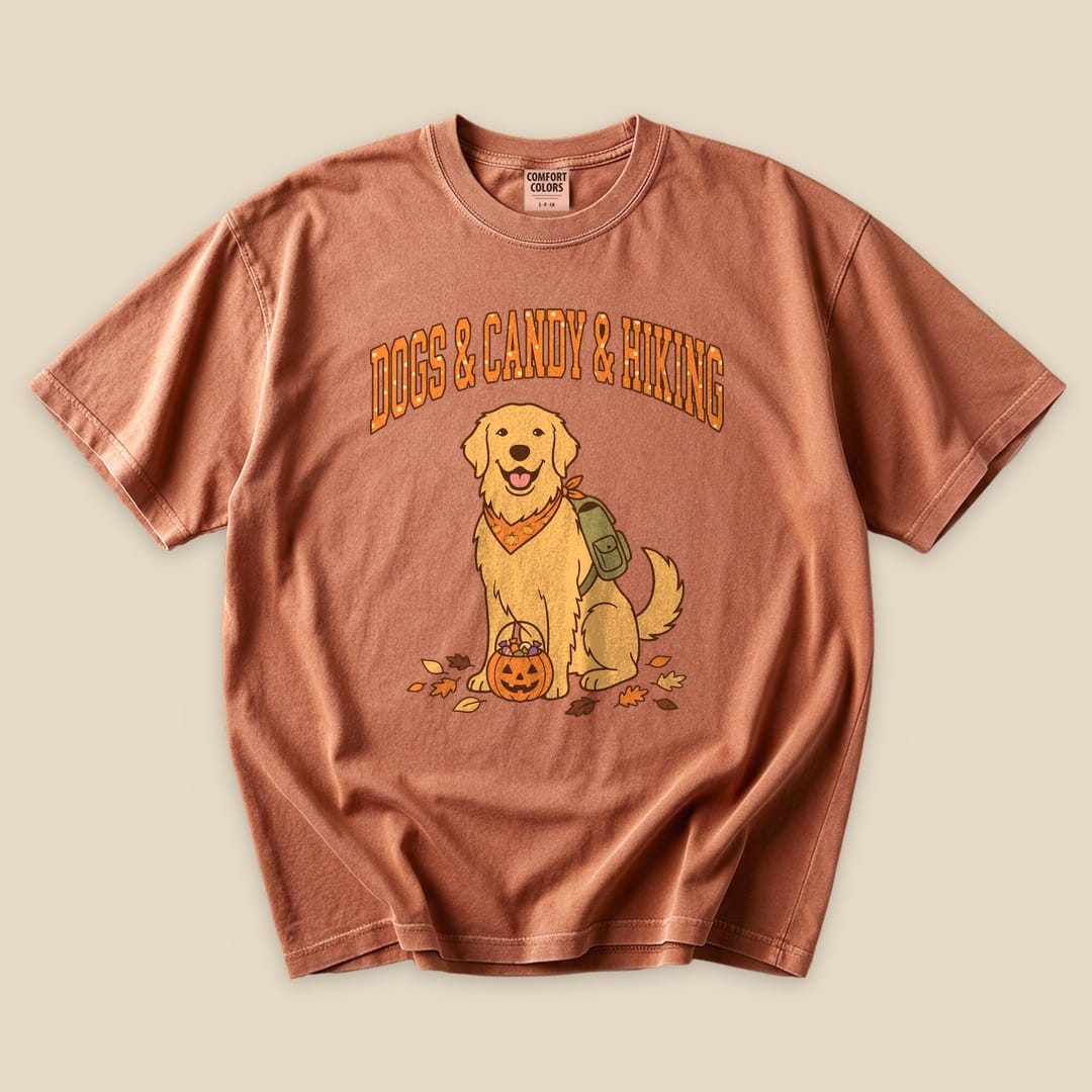 Graphic t-shirt featuring a smiling golden retriever with a pumpkin, accompanied by the text "Dogs & Candy & Hiking.