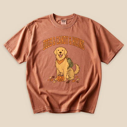 Graphic t-shirt featuring a smiling golden retriever with a pumpkin, accompanied by the text "Dogs & Candy & Hiking.