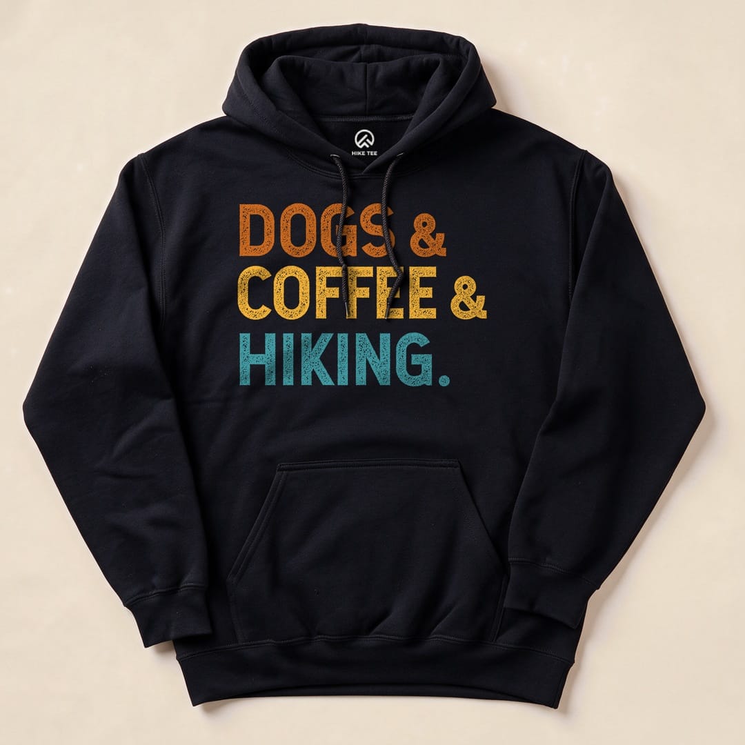 A black hoodie featuring the phrase "DOGS & COFFEE & HIKING" in vibrant orange, yellow, and teal graphic text.