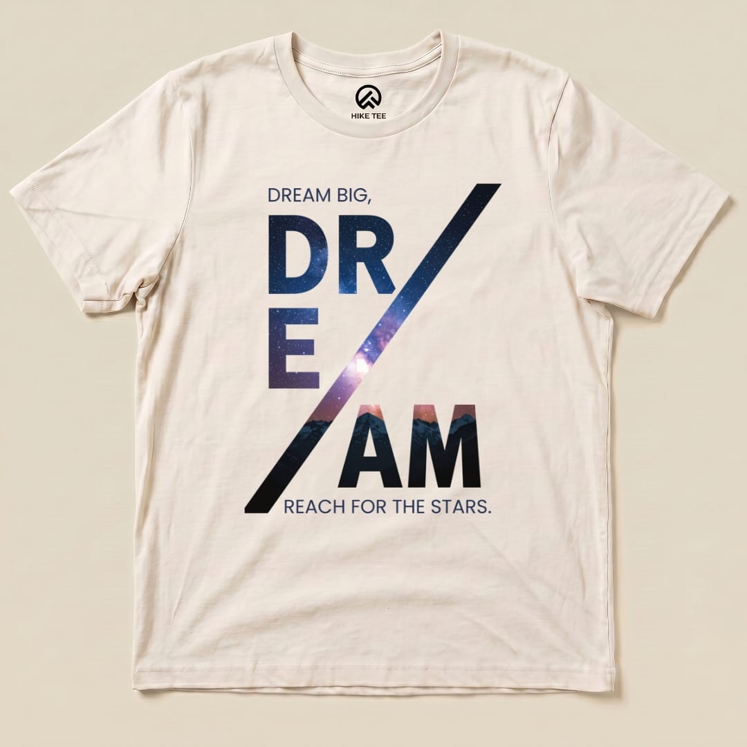 A graphic t-shirt featuring the text "DREAM BIG, DREAM REACH FOR THE STARS" with a starry background on a light fabric.