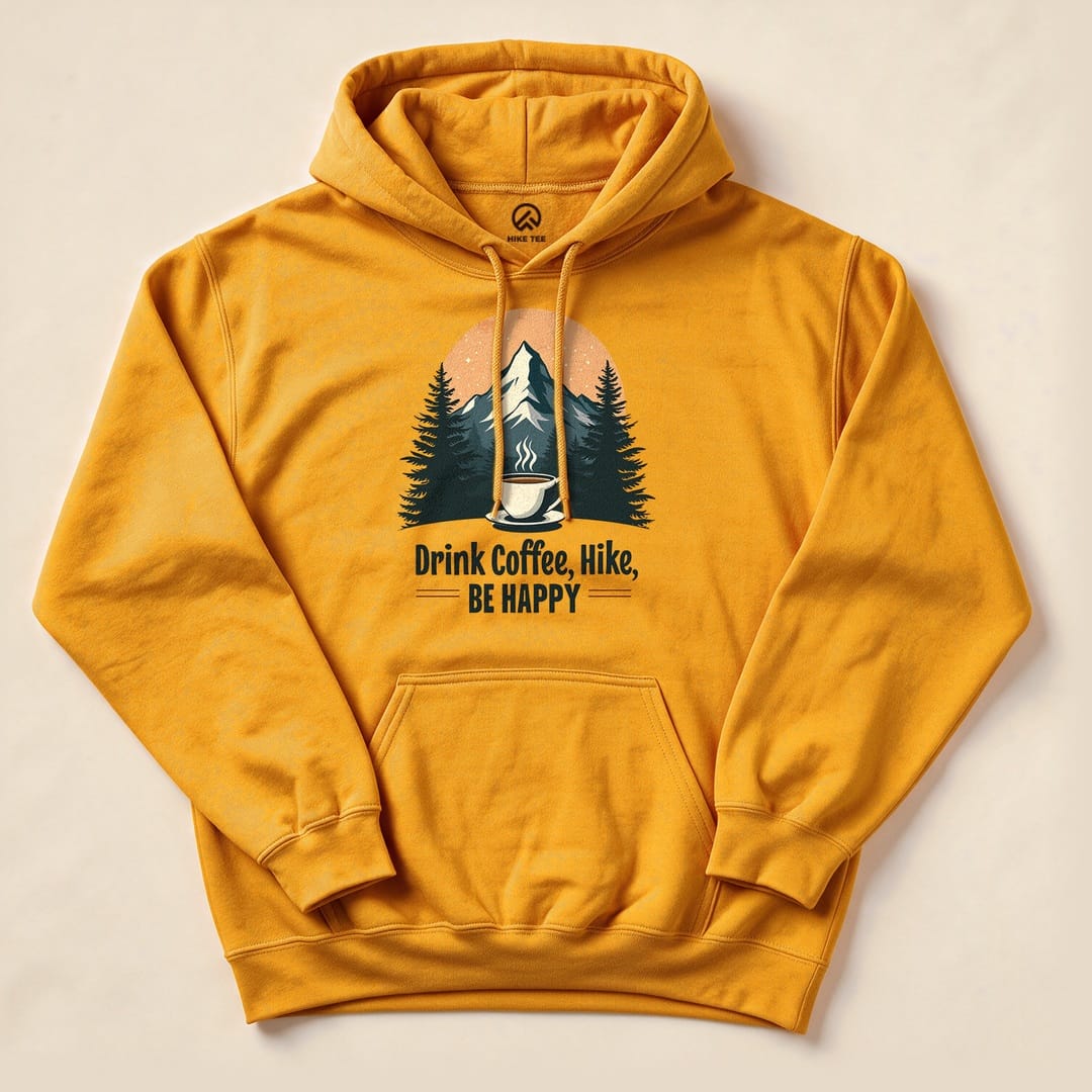 A graphic hoodie in vibrant yellow featuring a mountain scene with trees and the text "Drink Coffee, Hike, Be Happy.