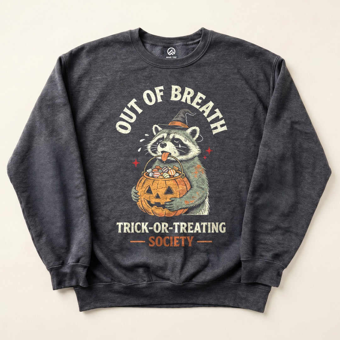Dark Heather Out of Breath Trick-or-Treating Society Sweatshirt with a tired raccoon holding a jack-o-lantern candy bucket graphic
