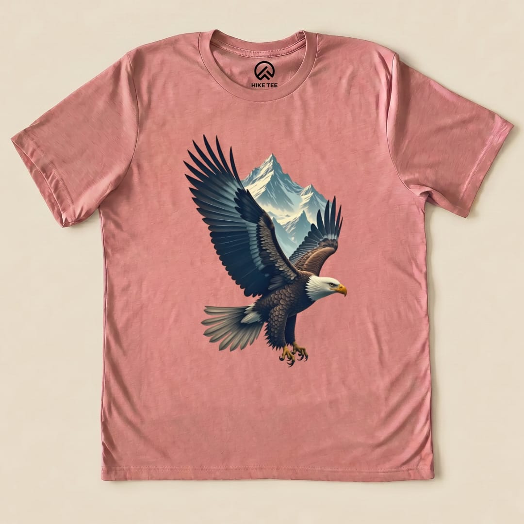 A graphic t-shirt featuring a soaring eagle and mountain design on a pink background, labeled as the Eagle and Mountain Shirt.