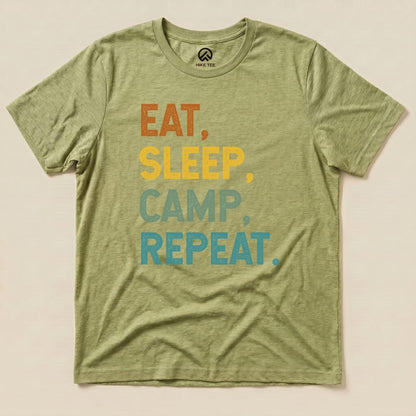 A flat olive green graphic t-shirt featuring the slogan "Eat, Sleep, Camp, Repeat" in bold, colorful letters.