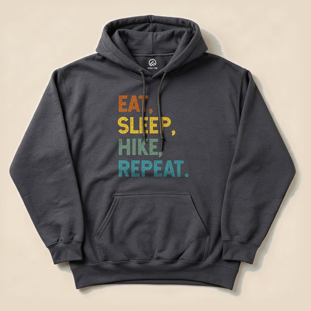 A dark gray hoodie featuring the phrase "Eat, Sleep, Hike, Repeat" in colorful, bold letters, displayed flat.