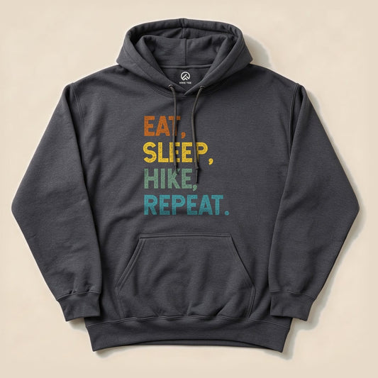 A dark gray hoodie featuring the phrase "Eat, Sleep, Hike, Repeat" in colorful, bold letters, displayed flat.