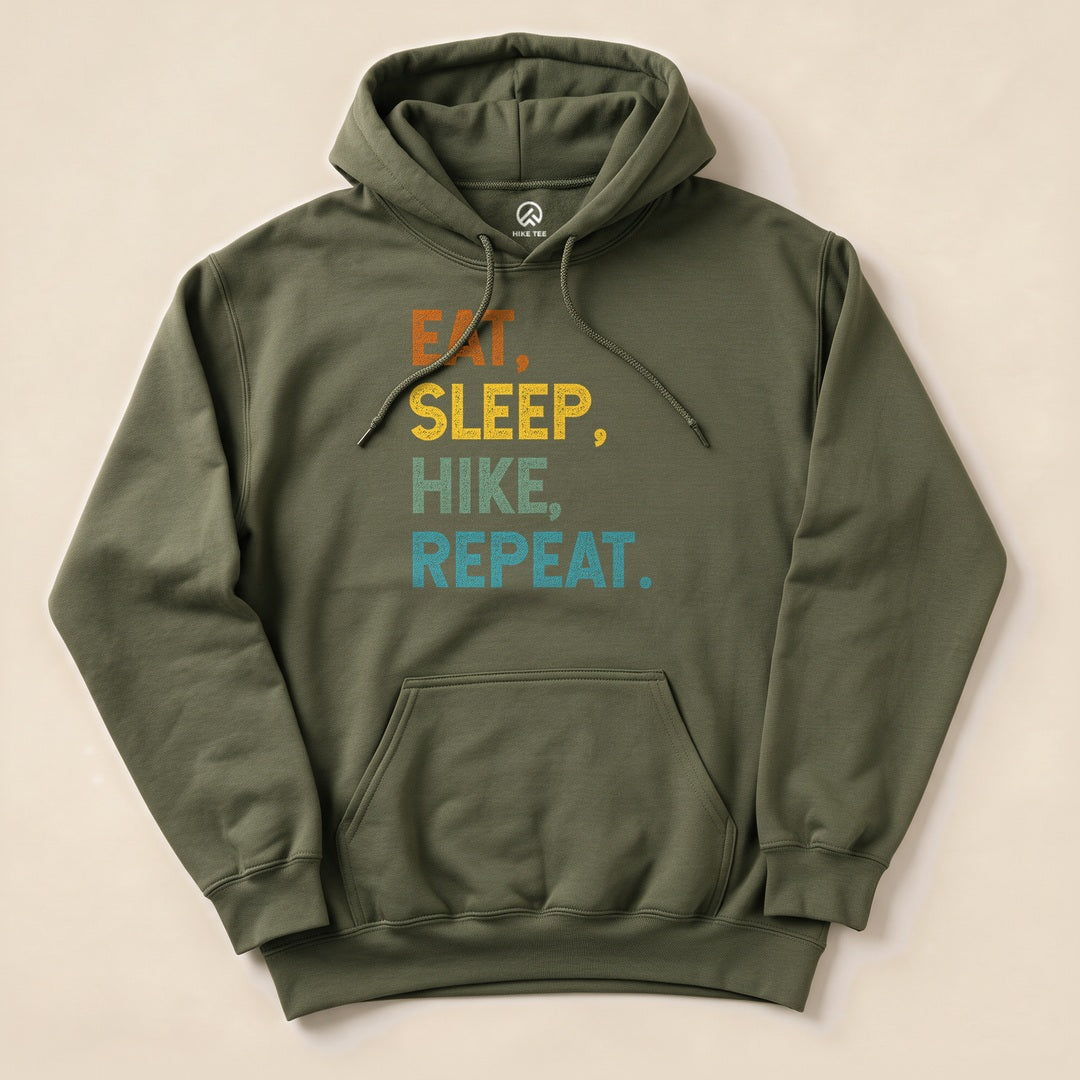 An olive green hoodie featuring the printed text "Eat, Sleep, Hike, Repeat" in orange and blue shades, designed for outdoor enthusiasts.