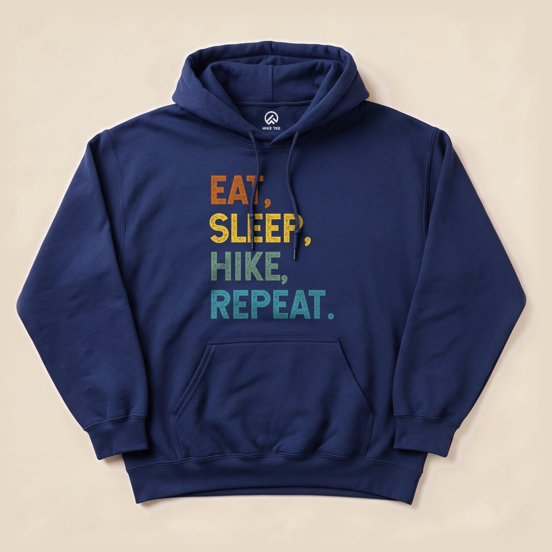 A navy blue hoodie features the graphic text "EAT, SLEEP, HIKE, REPEAT" in vibrant colors, showcasing a playful outdoor theme.
