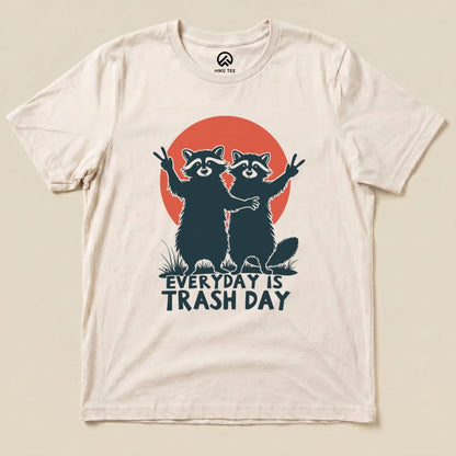 Graphic t-shirt featuring two raccoons with peace signs, a red sunset, and the slogan "Everyday is Trash Day.