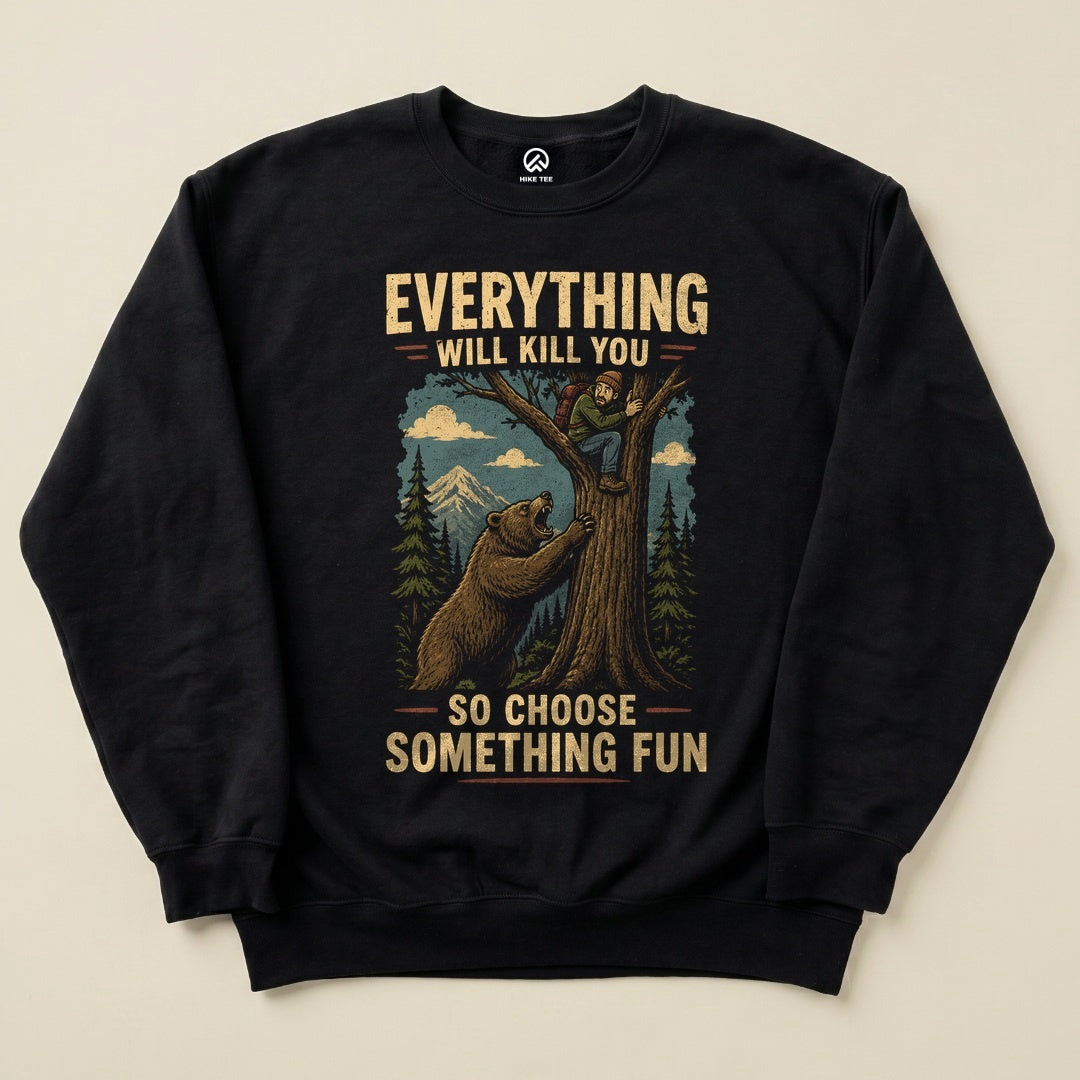 The Everything Will Kill You Sweatshirt features a humorous graphic of a bear and a hiker in a forest setting, with mountains in the background.