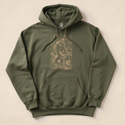 A green "Walking the Dog Hoodie" featuring a graphic of Bigfoot walking a small dog in a forest scene, laid flat on a light background.