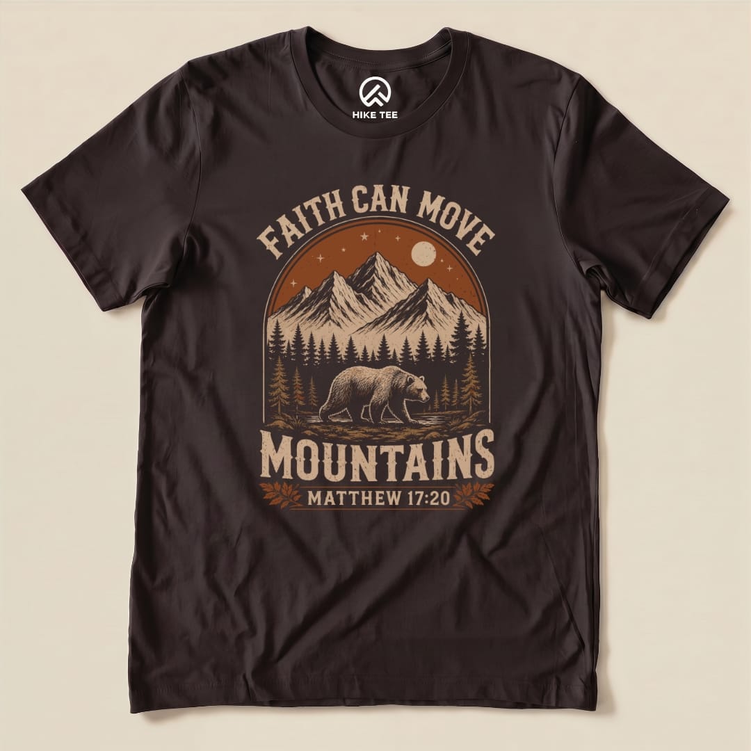 A graphic t-shirt featuring the phrase "Faith Can Move Mountains" with mountains, a bear, and the verse Matthew 17:20.