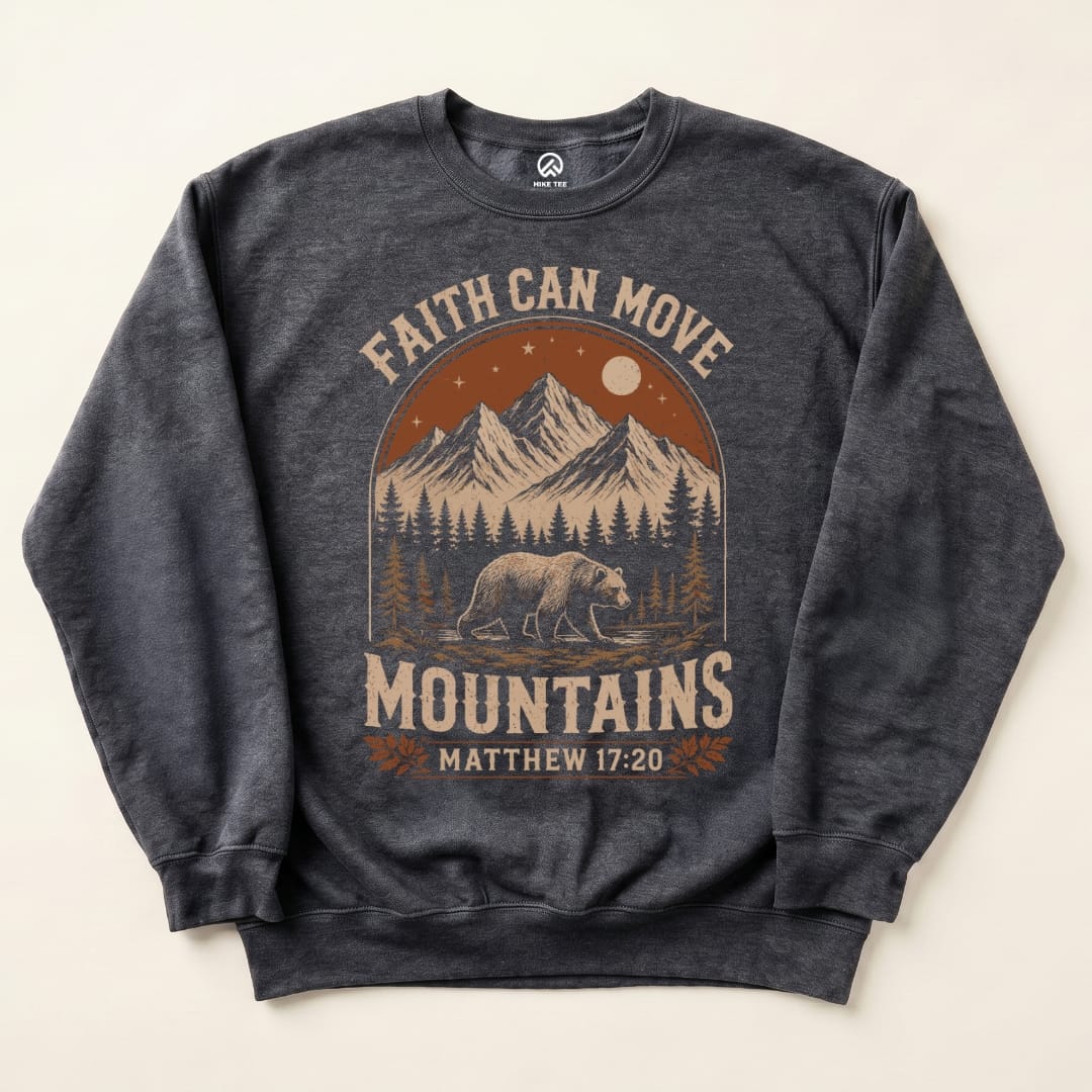 A dark sweatshirt featuring a graphic design with the slogan "Faith Can Move Mountains" and illustrations of mountains, a bear, and trees.