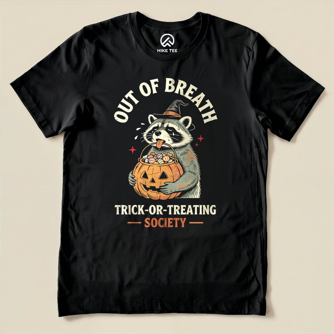 Black Out of Breath Trick-or-Treating Society Shirt with a raccoon witch holding a pumpkin full of candy graphic