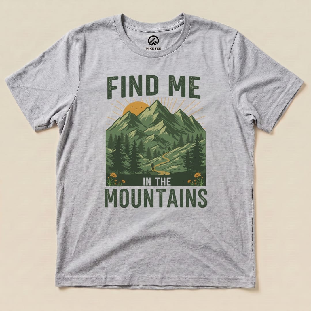 Light gray graphic t-shirt featuring a design with mountains, a sun, and the text "Find Me In The Mountains" below.