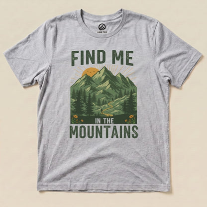 Light gray graphic t-shirt featuring a design with mountains, a sun, and the text "Find Me In The Mountains" below.