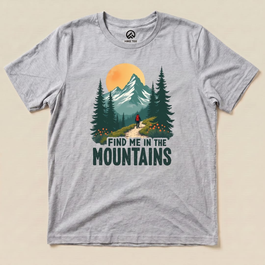 A gray graphic t-shirt displays the phrase "FIND ME IN THE MOUNTAINS" with an illustration of a hiker on a scenic mountain trail.