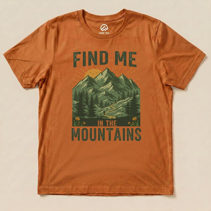 A graphic t-shirt in burnt orange features a mountainous landscape and the phrase "Find Me In The Mountains" in bold lettering.