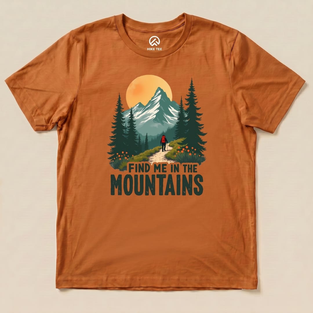 The orange graphic t-shirt features a mountain landscape with the words "FIND ME IN THE MOUNTAINS" printed prominently.