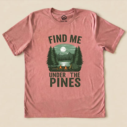 The graphic t-shirt features the phrase "Find Me Under The Pines" alongside a scenic design of trees, mountains, and a campfire.