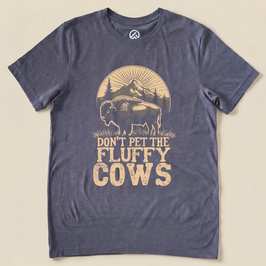 A graphic t-shirt features a bison illustration with the slogan "Don't Pet the Fluffy Cows," set against a mountain backdrop.
