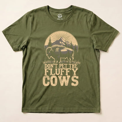 A graphic t-shirt in olive green featuring a fluffy bison with the text "DON'T PET THE FLUFFY COWS" beneath it.
