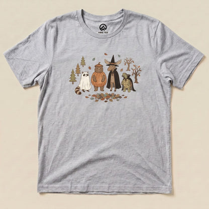 A graphic t-shirt featuring whimsical forest animals, including a bear and a raccoon, dressed for a costume party, titled "Forest Friends Costume Party Shirt.