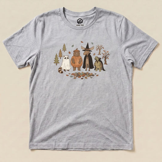 A graphic t-shirt featuring whimsical forest animals, including a bear and a raccoon, dressed for a costume party, titled "Forest Friends Costume Party Shirt.
