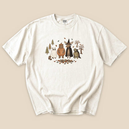 The Forest Friends Costume Party T-Shirt features a playful graphic of a bear, moose, raccoon, and ghost among trees and autumn leaves.