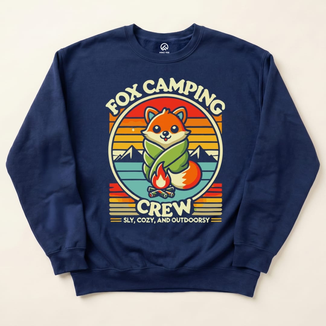 Navy blue sweatshirt featuring a playful fox graphic, wrapped in a blanket with the text "Fox Camping Crew" and a campfire design.