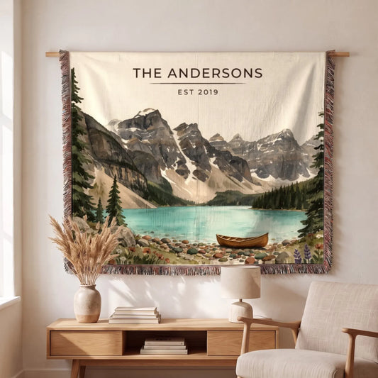 A beautifully designed Glacier Lake Canoe Woven Blanket features serene mountain scenery and tranquil waters, perfect for cozying up indoors.