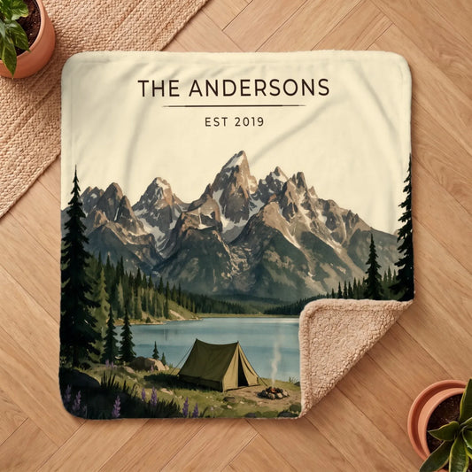 A cozy view of the Grand Teton Lake Campsite Sherpa Blanket featuring a serene mountain landscape and a camping scene.