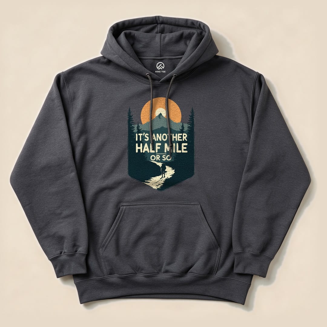 A dark gray Half Mile Hoodie featuring a graphic of a hiker on a trail with the slogan "It's Another Half Mile or So.
