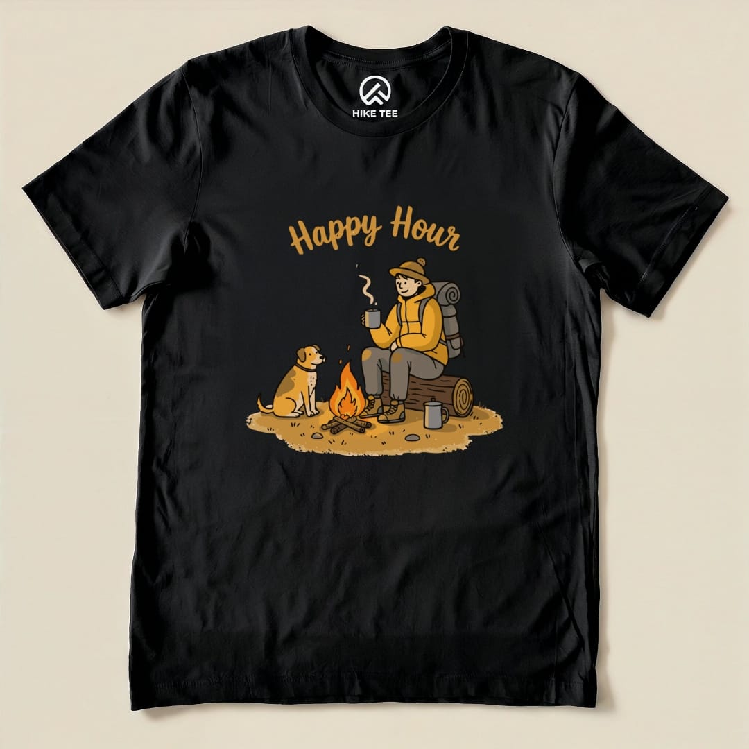 A graphic t-shirt featuring the slogan "Happy Hour" with a person sitting by a campfire and a dog, enjoying drinks outdoors.