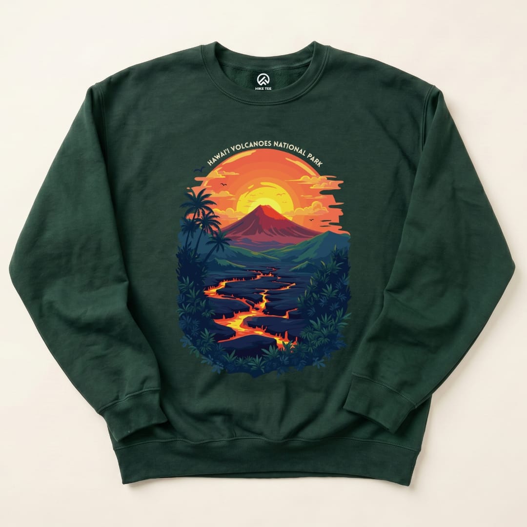 A dark green Hawai'i Volcanoes National Park Sweatshirt features a vibrant graphic of a volcano, sunset, and flowing lava.