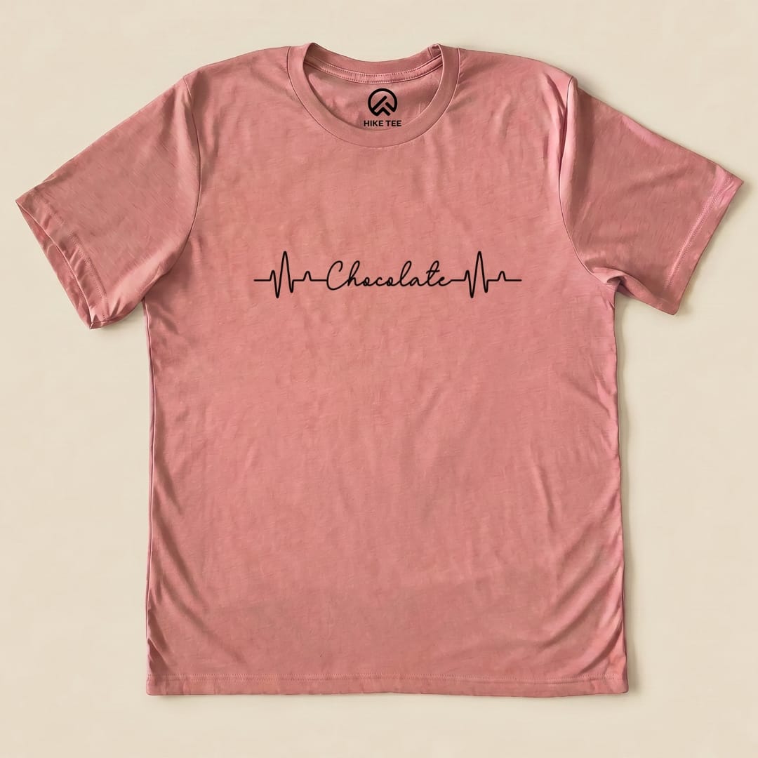 A pink graphic t-shirt featuring the phrase "Chocolate" with heartbeat lines, labeled as the Heart Beat Chocolate Shirt.
